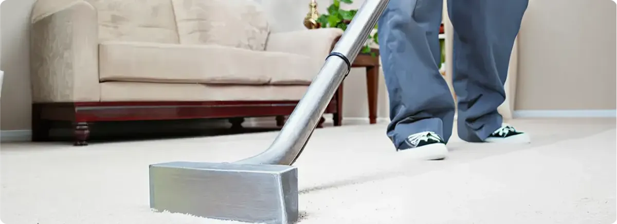 Carpet cleaning technician using a hot-water extraction wand on a light-colored carpet in a living room, San Diego, CA.