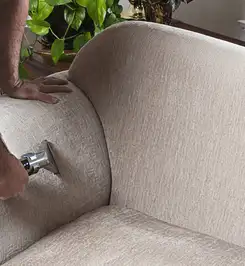 Professional upholstery cleaner deep-cleaning a fabric sofa with a handheld extraction tool and hose San Diego, CA.
